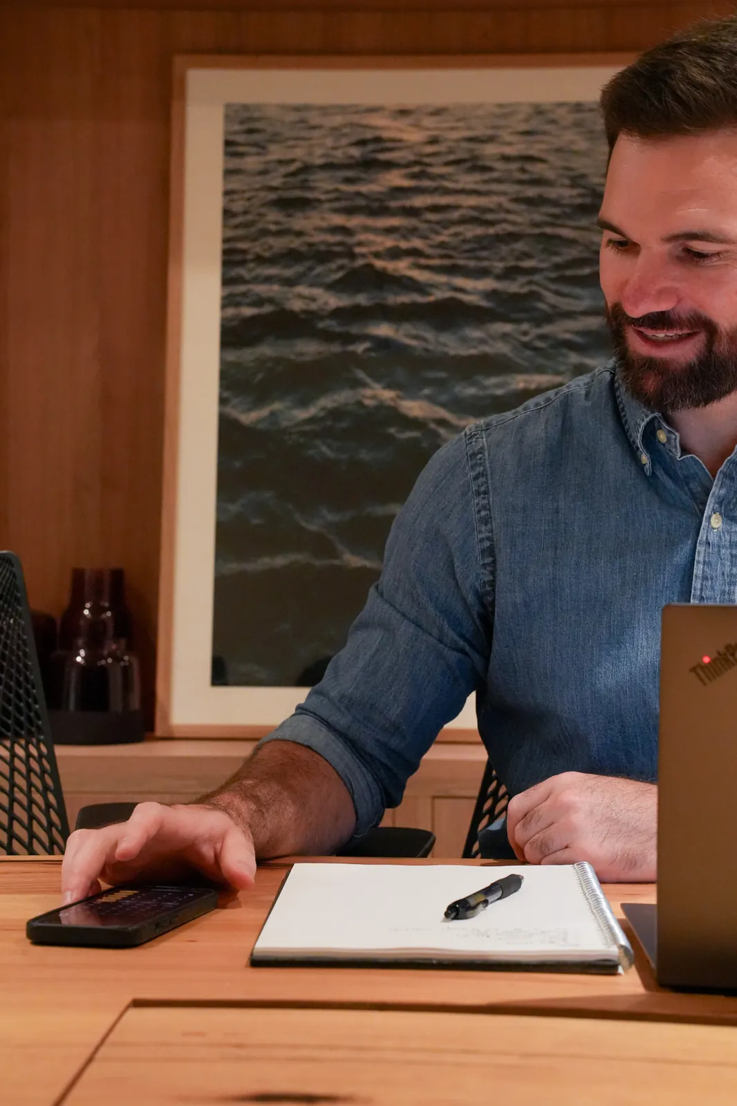 Jason smiling at his desk with a notebook and laptop