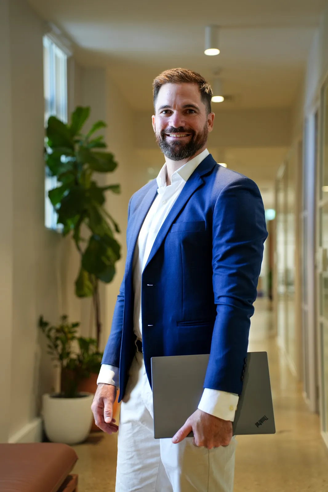 Jason standing in an office hallway holding a laptop